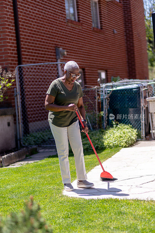 年长的女人清扫她的后院区域