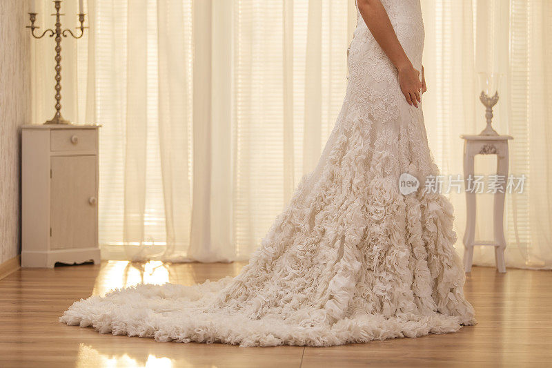 新娘穿着带褶边的婚纱，拖着长长的裙裾