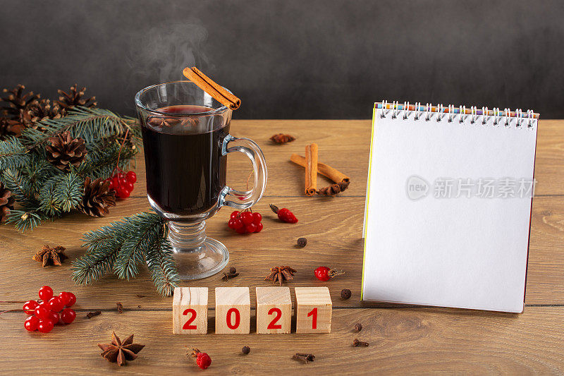 热红酒，圣诞树，装饰品，松果，待做清单。2021年在木制立方体上。空白,空的笔记本。写新年计划。