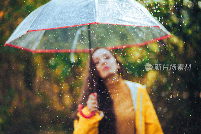 秋雨中带着透明塑料伞的快乐女人