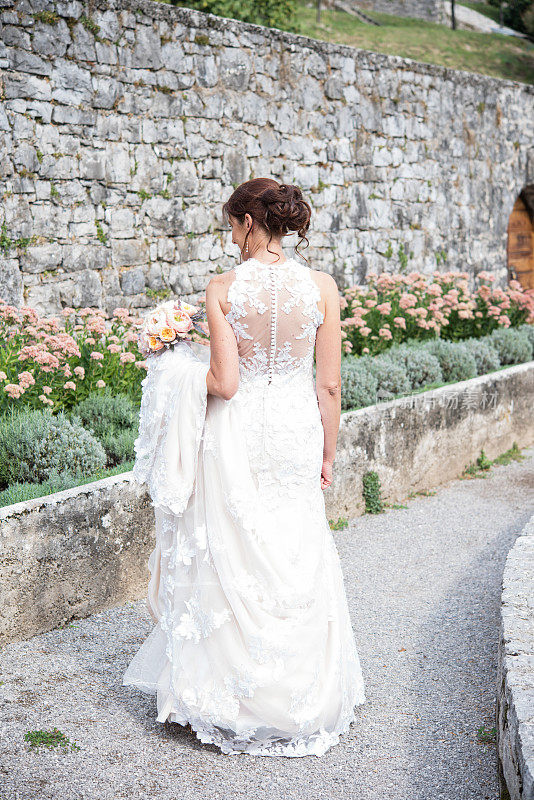穿着婚纱的新娘在观赏园散步，看花-后视图