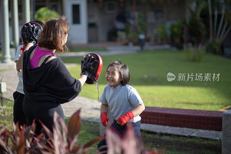 亚洲华人妈妈和孩子们在公园里玩得很开心。他们在训练跆拳道。泰拳，武术