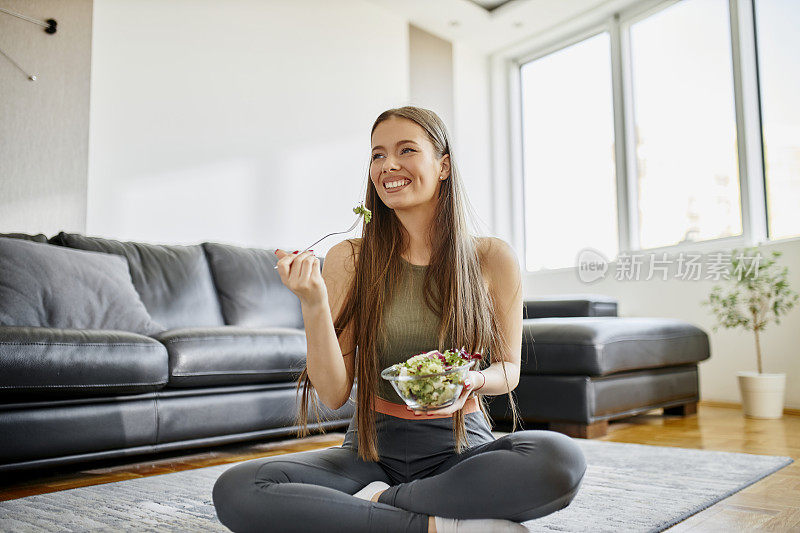 健身女性在剧烈的家庭运动后吃新鲜的沙拉