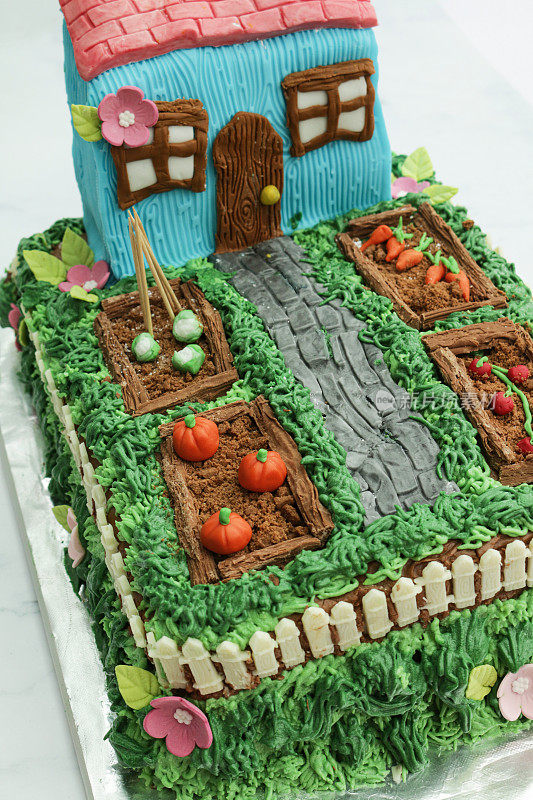自制的，装饰蛋糕设计成小屋和花园的蔬菜床，黄油糖霜草与巧克力片和饼干屑土壤菜地，方糖糖霜南瓜，西红柿，花椰菜和胡萝卜，前景突出
