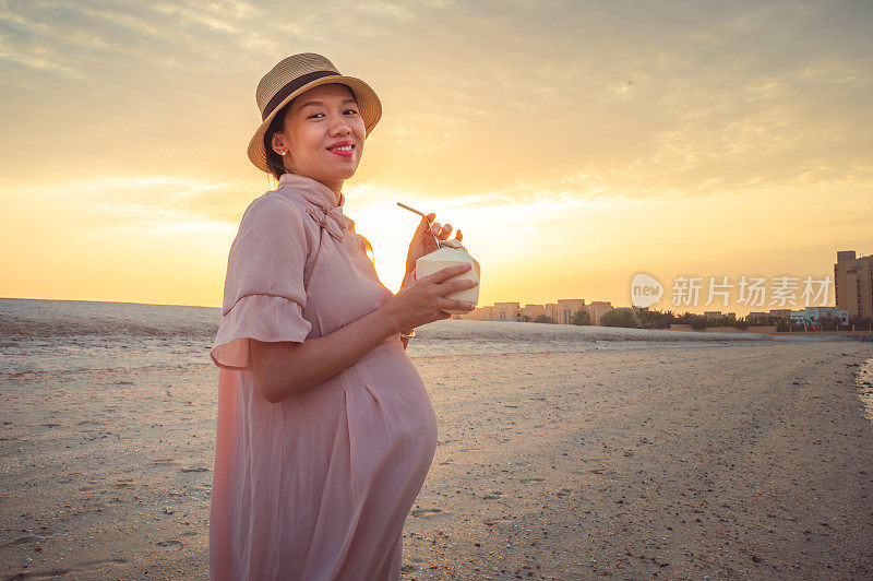 孕妇花时间在海滩上有新鲜的椰子在海边日落