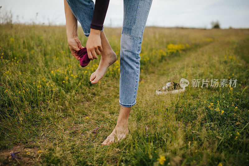 在草地上穿袜子的女人