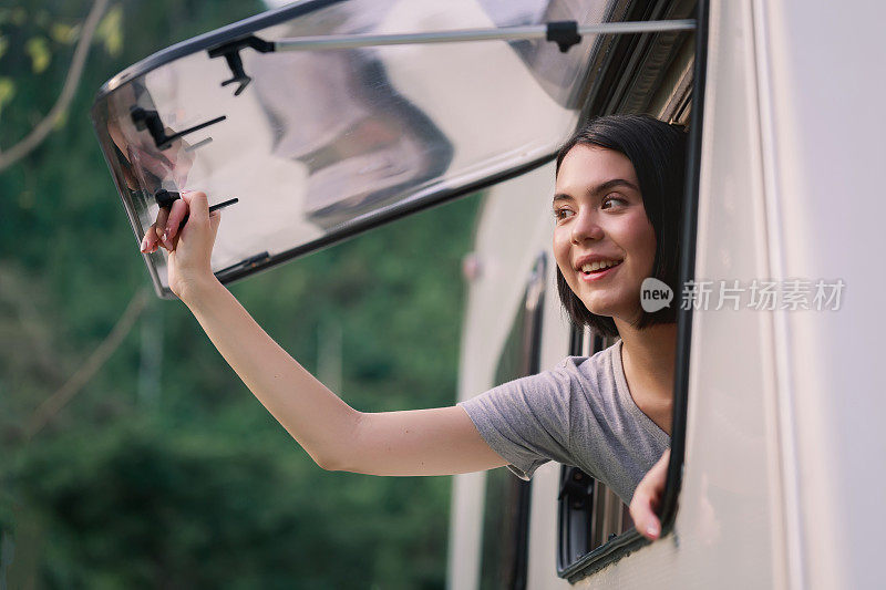 年轻漂亮的白人女人，在公路旅行，早上打开露营车的窗户。舒适的露营车设置。21、千禧年旅行潮流，冒险路上行