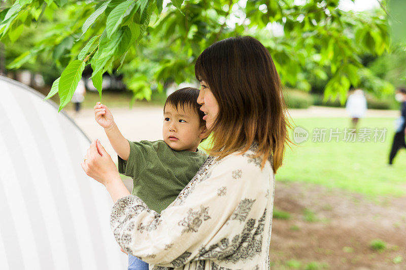 一个日本小男孩和他年轻的妈妈在公园里玩