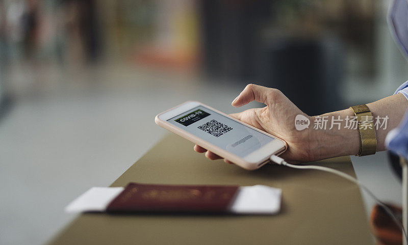 一名匿名女商人在机场值机柜台使用手机上的电子护照应用程序