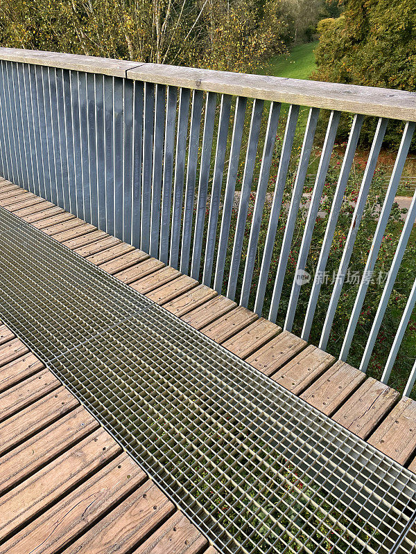 秋日阳光下的人行天桥近景，木桥面和栏杆，木顶栏杆和金属栏杆，金属格栅和方孔排水