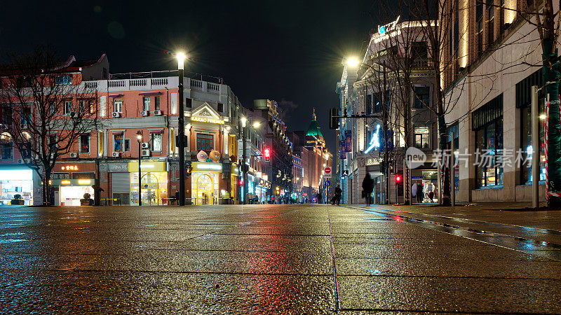 下雨天的上海南京路夜景，长时间曝光对称构图，美丽的霓虹灯和反射在潮湿的地面上。