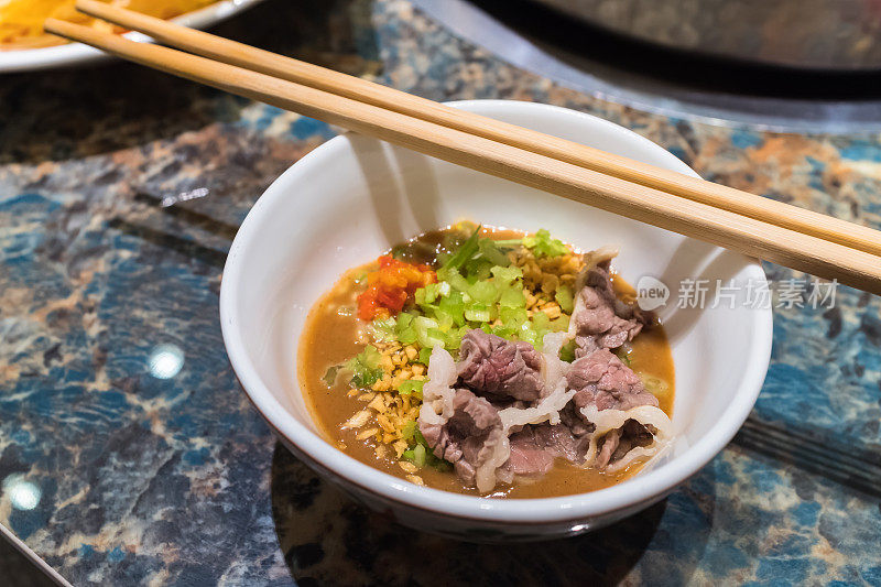 中国福建潮汕牛肉火锅，一块拉丝的牛肉蘸在碗里随时可以吃