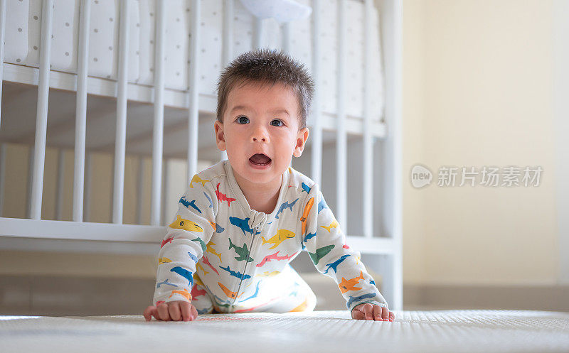 小男孩在卧室地板上的婴儿安全软游戏垫上爬行