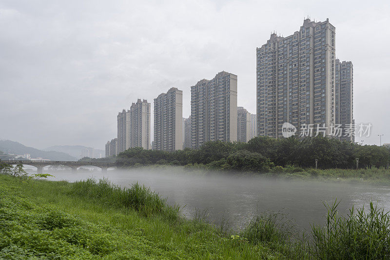 晨雾中的城市映衬着湖边的高楼大厦