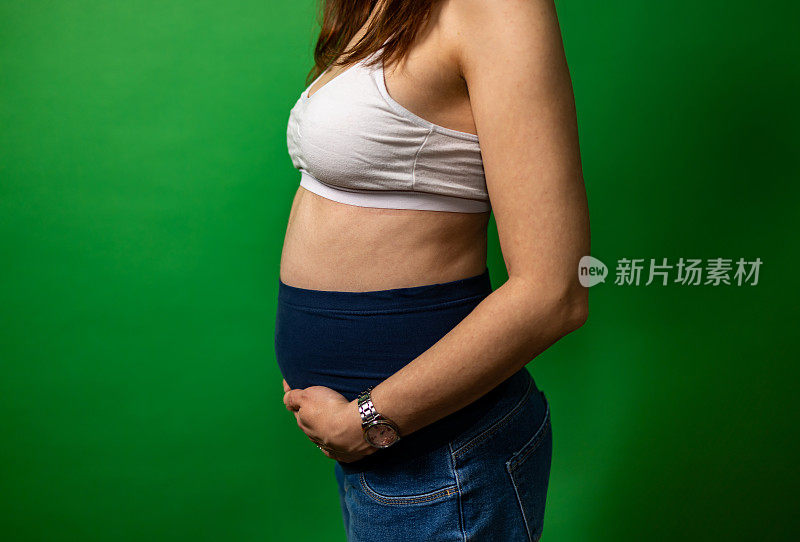 快乐的孕妇在彩色背景。年轻的母亲要生孩子了。副本的空间。