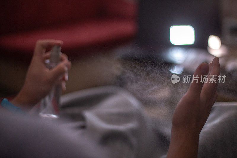 近景的人的手和消毒喷雾瓶在黑暗的背景。手卫生。冠状病毒疫情防控措施