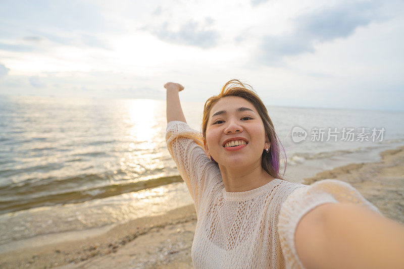 美丽的亚洲女人用相机拍摄海景，所以可以记住这一刻。
