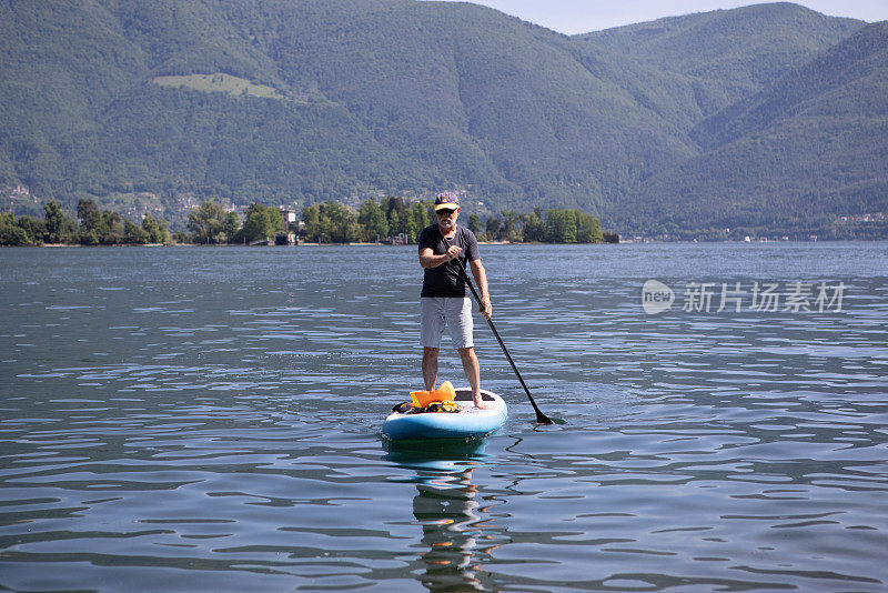 一位资深男子在湖上练习站立式桨板