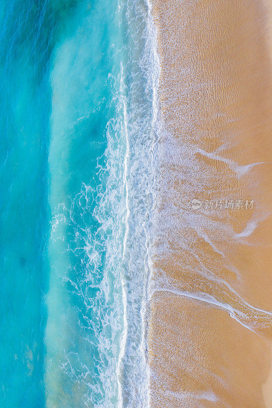 海滩的场景从上面-蓝色的海浪打在沙滩上。