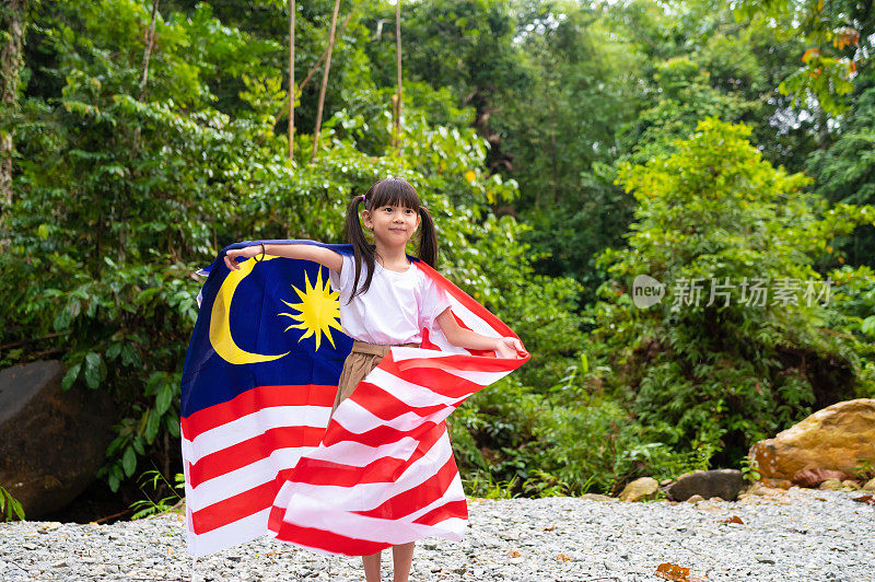 年轻的亚洲女孩挥舞着马来西亚国旗庆祝马来西亚国庆日