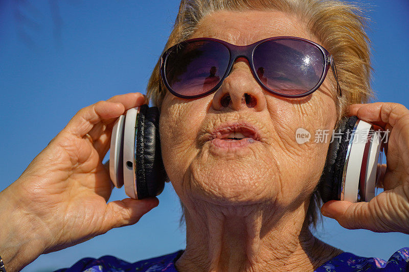 老妇人在公园里戴着耳机唱歌。痴呆的治疗