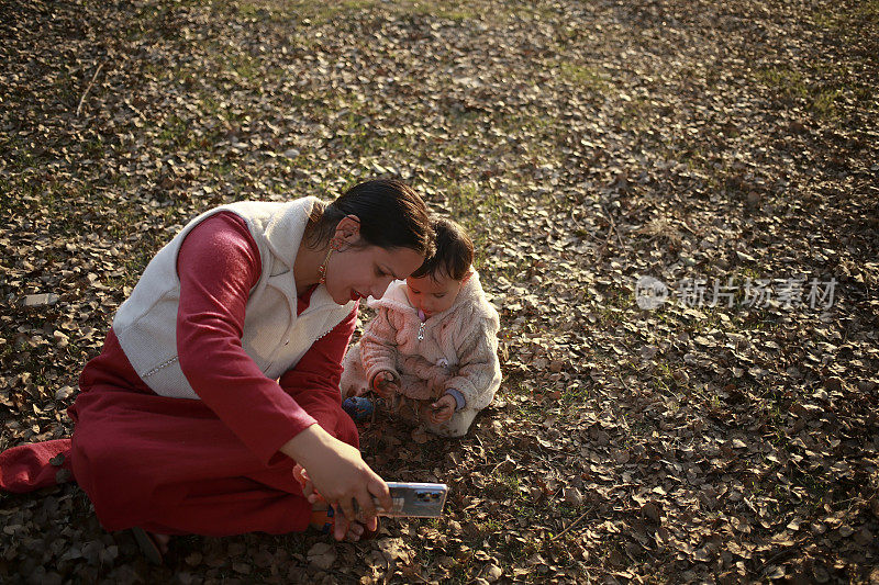 秋天，妈妈和女儿在公园里用手机自拍