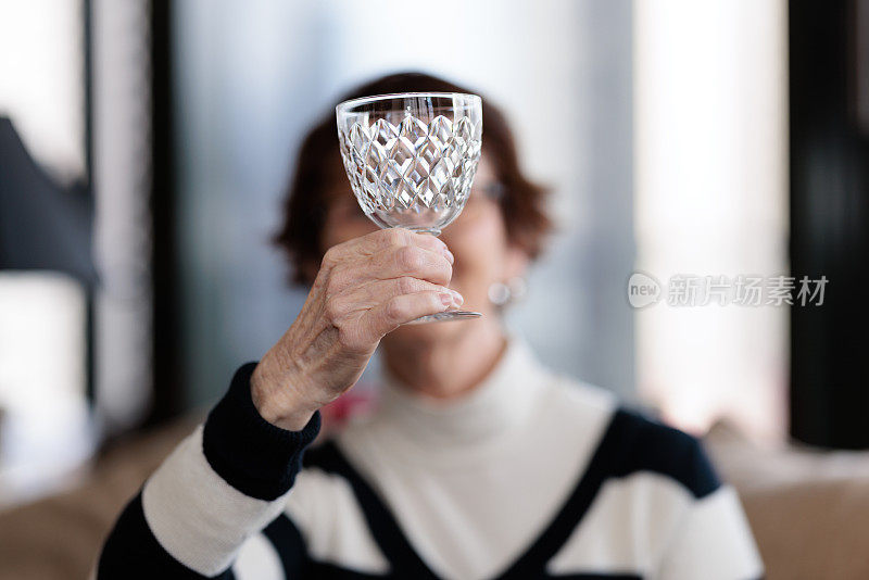 一名女子拿着酒杯对着灯光检查酒杯的状况