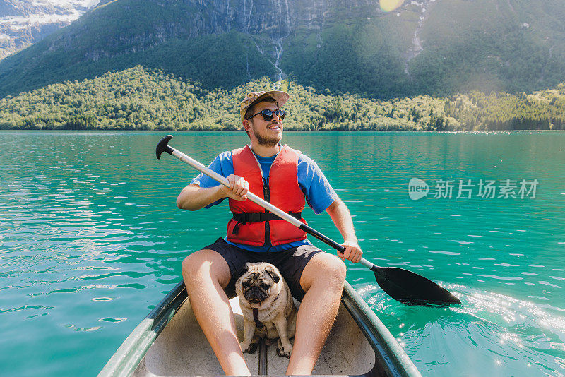 一名男子和狗在挪威风景秀丽的洛瓦特内特湖划独木舟的正面视图