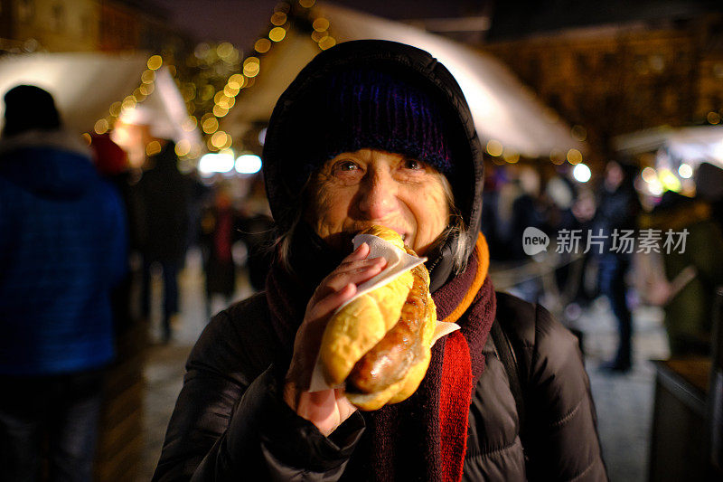 成熟女子在圣诞市场吃热狗