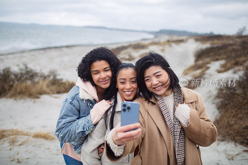 三个年轻女子在海滩上自拍