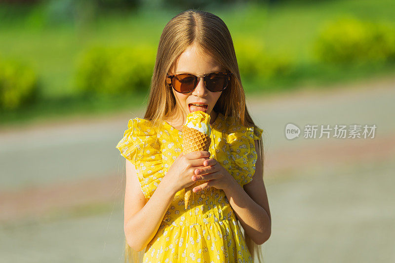 戴着墨镜，穿黄色裙子的金发女孩在吃冰淇淋。夏天的生活方式。童年