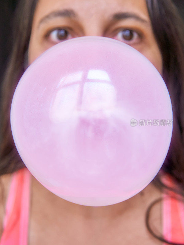 一个巨大的泡泡糖气球快要在中年女人脸上爆炸了