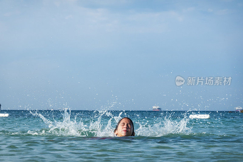 他用手在海里泼水。一个夏天的早晨。忒涅多斯岛。爱琴海北部，12岁的帅哥。长头发的