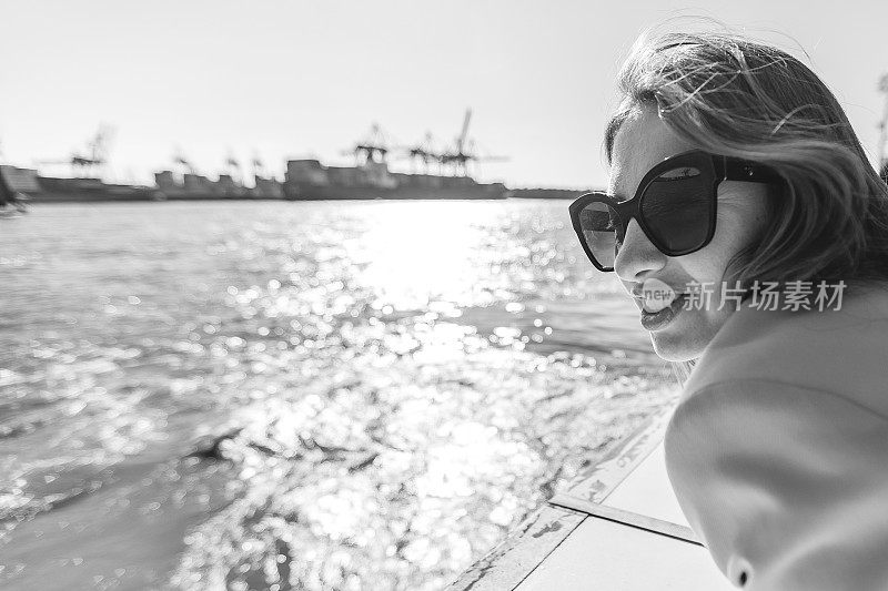 黑白女性肖像，一个美丽的时尚女人戴着太阳镜和外套在户外。游艇上好人的生活方式摄影。