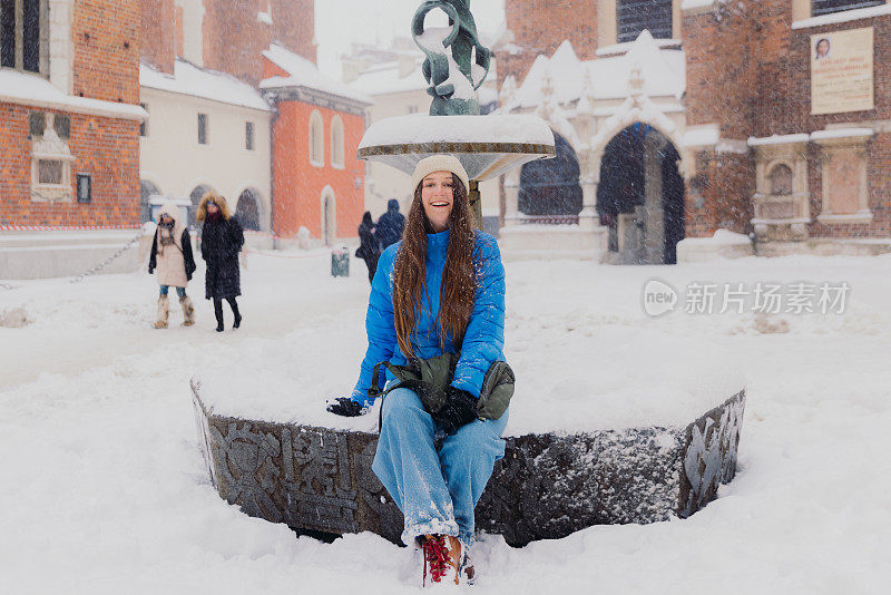 快乐的女人背着背包，在克拉科夫思考下雪的圣诞节