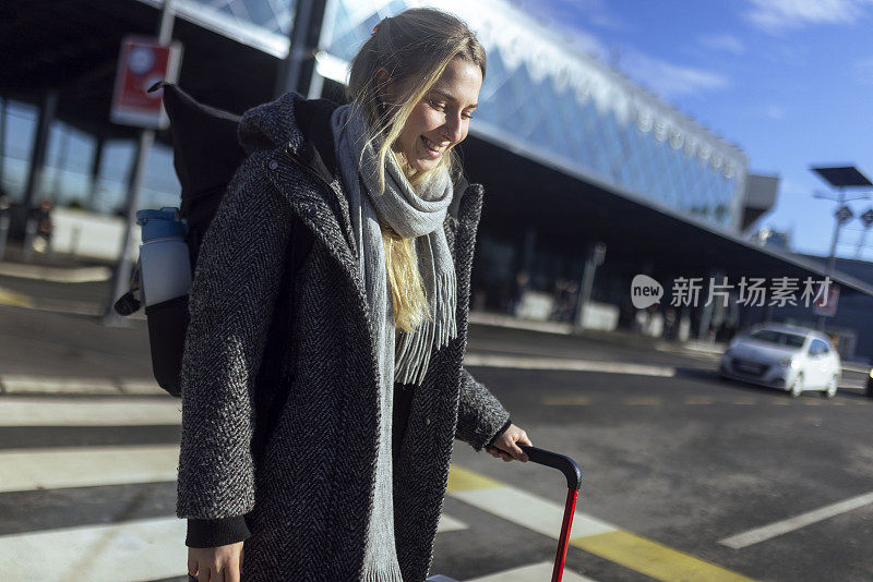 一个围着围巾的女人拖着行李箱离开了机场。她刚徒步旅行回来