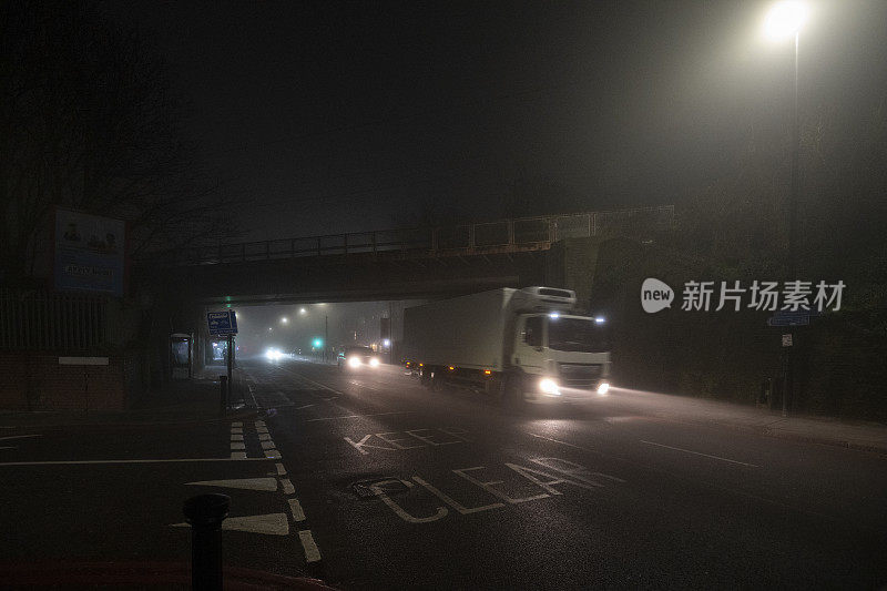 卡车在城市的夜晚在雾中行驶