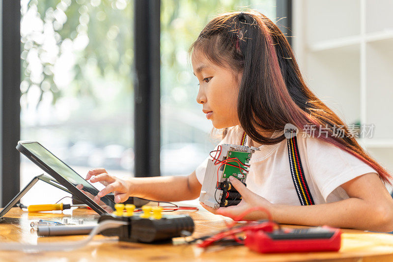 小女孩一边在家组装机器人，一边用平板电脑在网上搜索机器人套件的组装说明