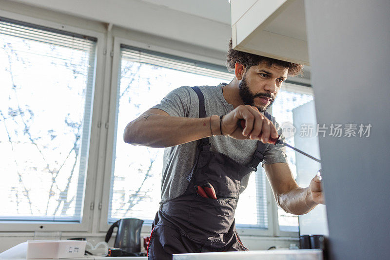 西班牙裔水管工正在修理客户家厨房水槽的漏洞