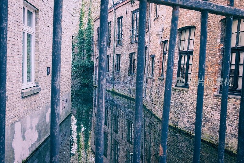 宁静的运河与旧砖建筑和金属酒吧的倒影，唤起了宁静的欧洲城市景观。