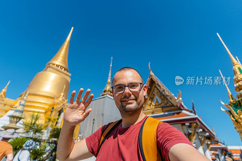 在泰国曼谷的玉佛寺，一名年轻人正在和玉佛寺进行视频通话