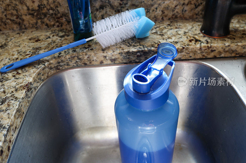 清洗厨房水槽里一个脏的可重复使用的塑料水瓶