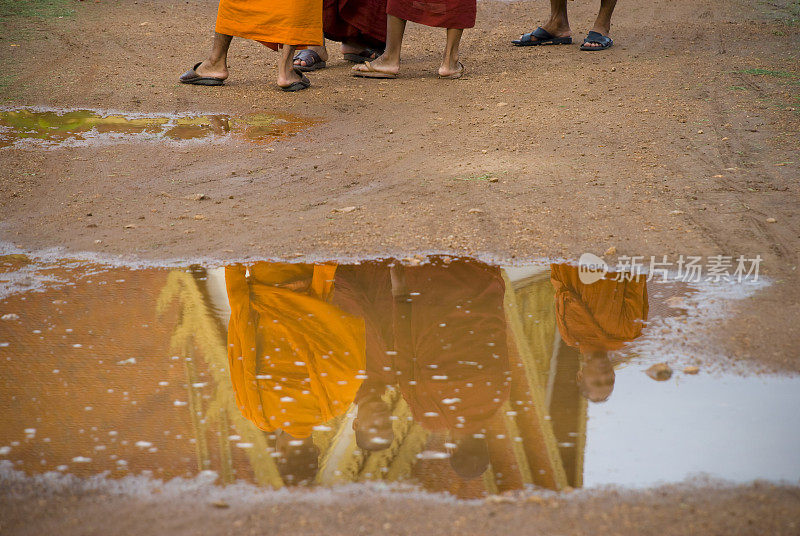 佛教僧侣在金边的雨坑中倒影