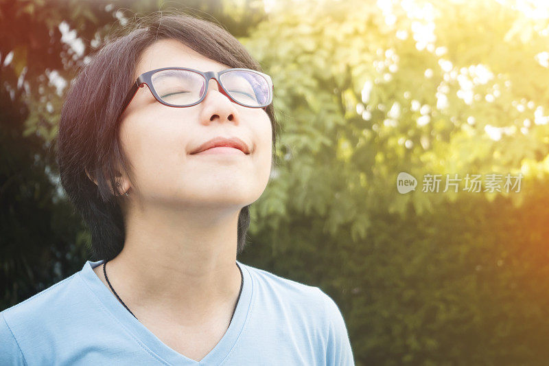 戴眼镜的女孩在公园里深呼吸新鲜空气。
