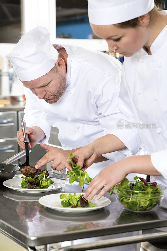 两名专职厨师准备牛排菜肴在美食餐厅