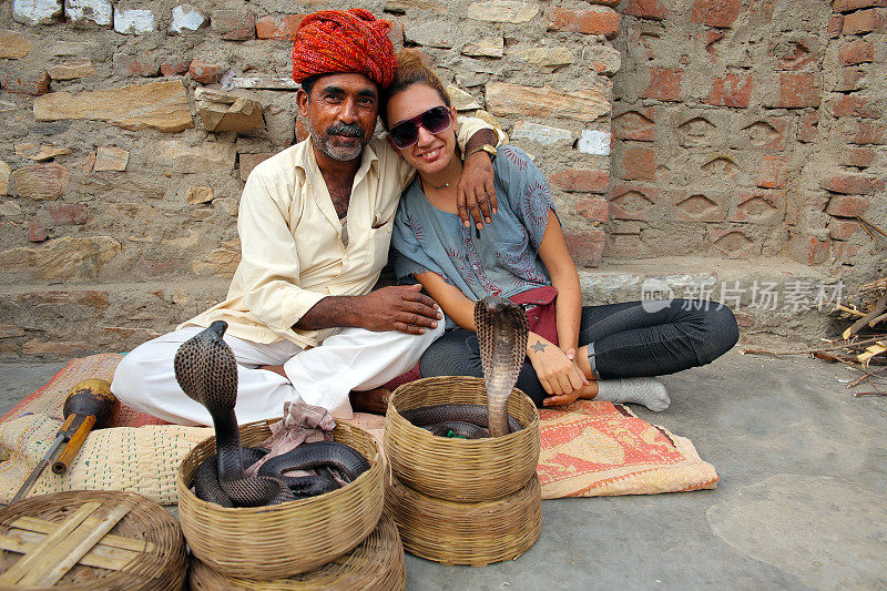 游客摆姿势与印度眼镜蛇魔术师合影