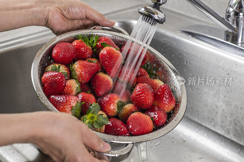一个装满草莓的银滤锅正在被清洗