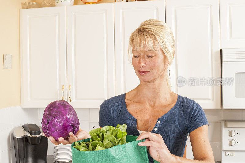 一名妇女正在从回收的杂货店绿色袋子里取出食物。