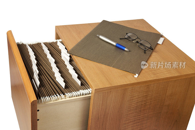 文件柜顶部有笔、眼镜和文件夹，打开的抽屉