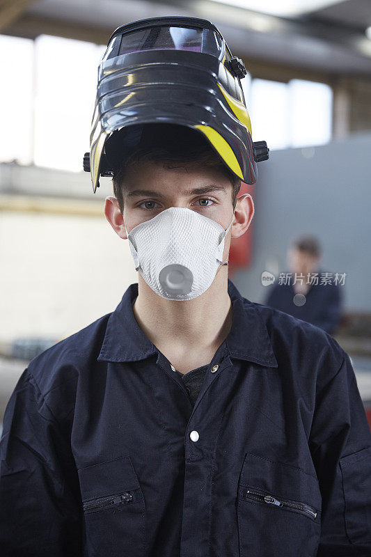 在钢铁制造厂戴口罩的年轻学徒